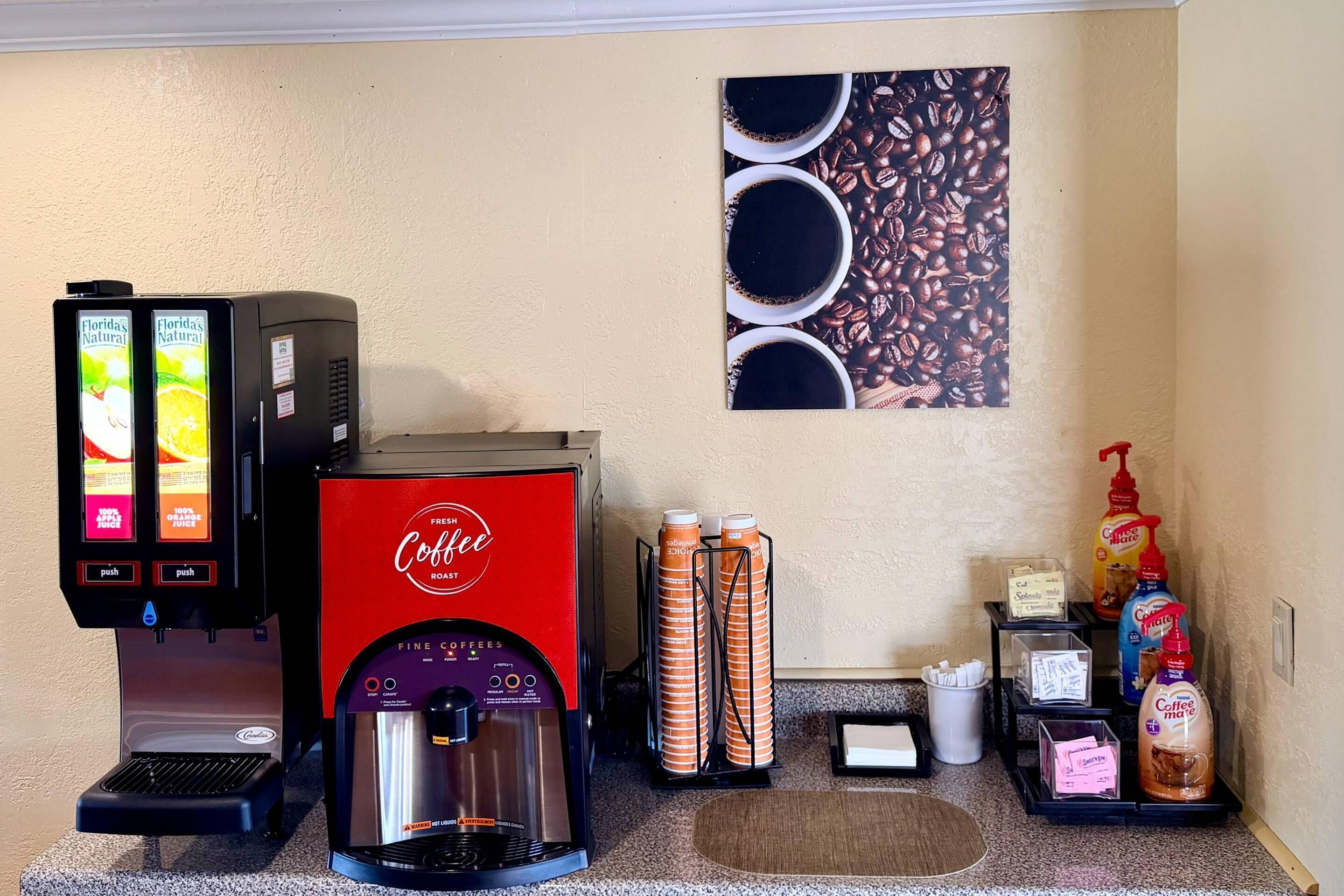 Una estación de café con una máquina de café, un dispensador de café y una exhibición de tazas de café.