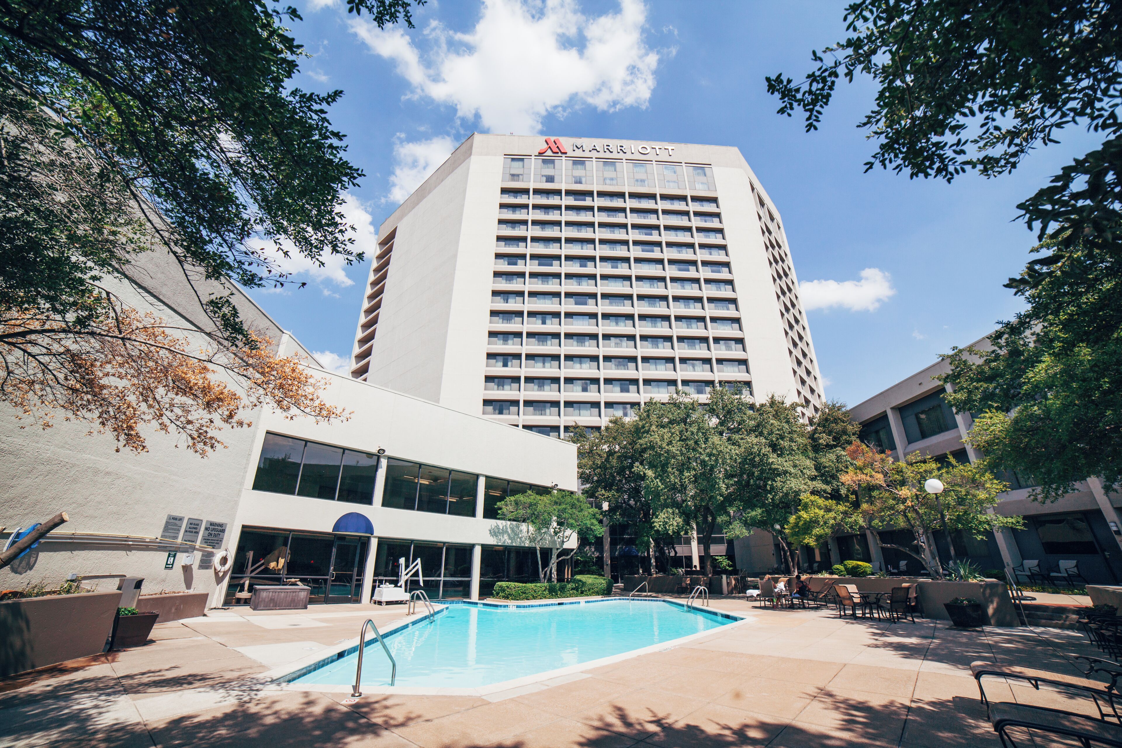 Un hotel con piscina, asientos al aire libre y un letrero de Marriott.