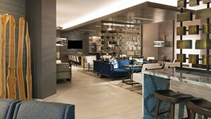 Un salon moderne avec un canapé bleu, une table basse et un coin bar équipé de tabourets.