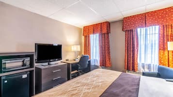 Une chambre d’hôtel équipée d’un lit, d’un bureau, d’une télévision, d’un four à micro-ondes et d’un mini-réfrigérateur.