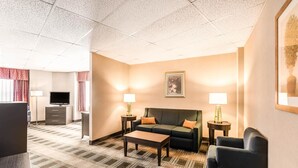 Habitación de hotel con sofá, mesa de centro, televisor, cómoda y dos lámparas.