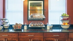 Una mesa de desayuno buffet con diversos alimentos y un bol de fruta.