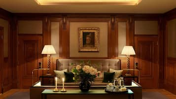 A well-lit room with a sofa, two lamps, a vase with flowers, and a framed picture on the wall.