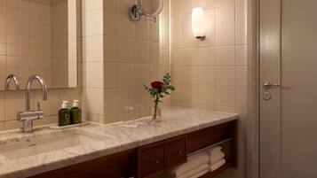 A bathroom with a marble sink, a mirror, a toilet, and a shower.