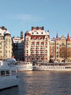 A river with boats and a row of historic buildings with red and white facades.