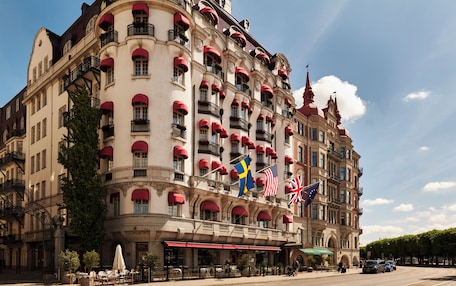 A historic building with multiple balconies, flags, and a classic architectural style.