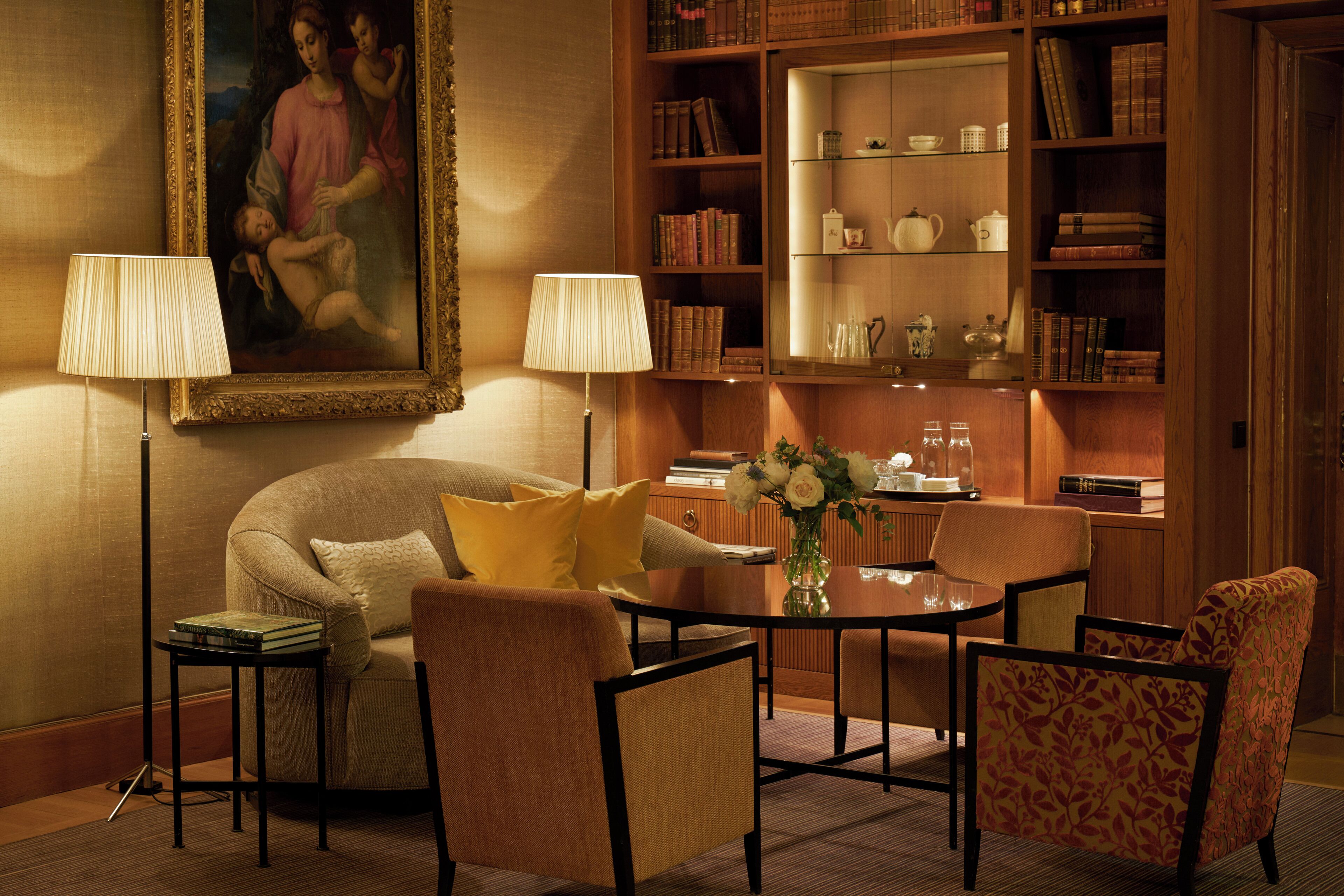A cozy living room with a sofa, armchairs, a coffee table, and a bookshelf filled with books and decorative items.