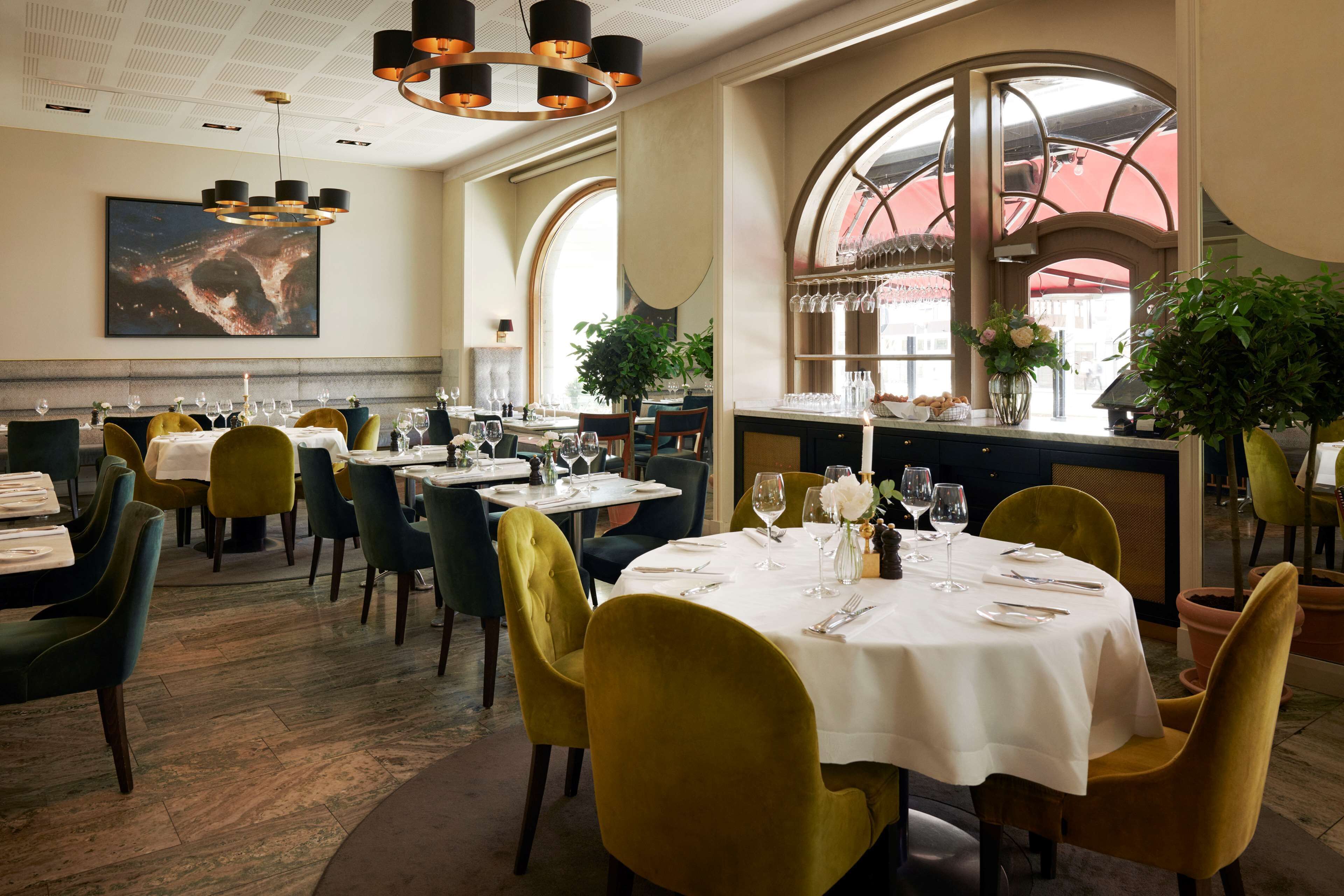 A restaurant with round tables, chairs, and a large window.