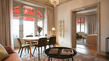 Ein geräumiges Wohnzimmer mit Essbereich, einer Chandelüster und Blick durch eine geöffnete Tür.