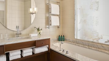Un baño moderno con un lavabo de mármol, un espejo grande, un perchero para toallas y una bañera.