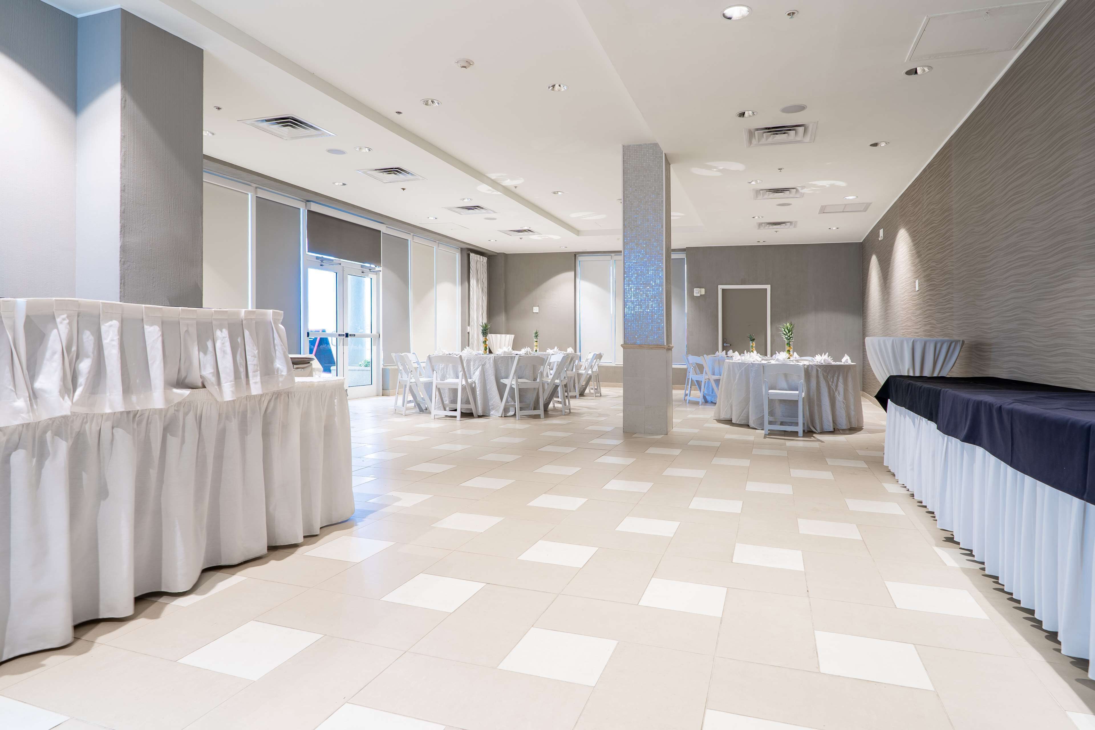 En rummelig hotellobby med højt til loftet, store vinduer og et skakmønstret gulv.