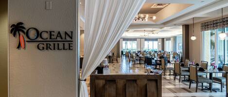 A restaurant interior with a check-in counter, dining tables, and chairs.