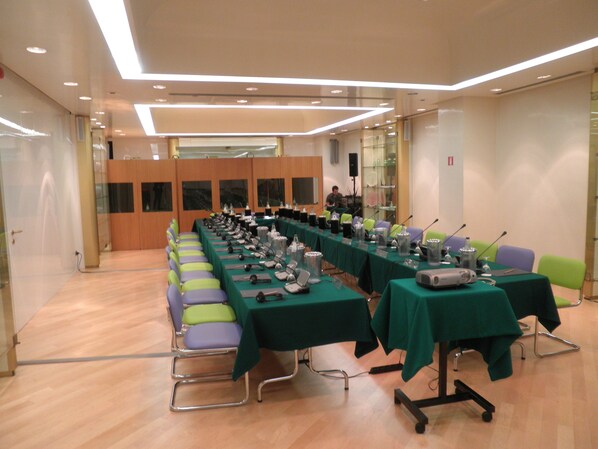 Un salón de conferencias con una larga mesa, sillas y un sistema de sonido.