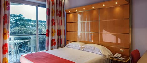 Una habitación de hotel con una cama grande, un escritorio y vistas a árboles por la ventana.