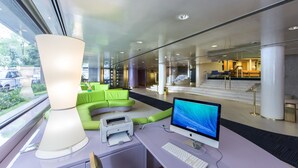 A modern hotel lobby with a desk, computer, printer, and a large window.