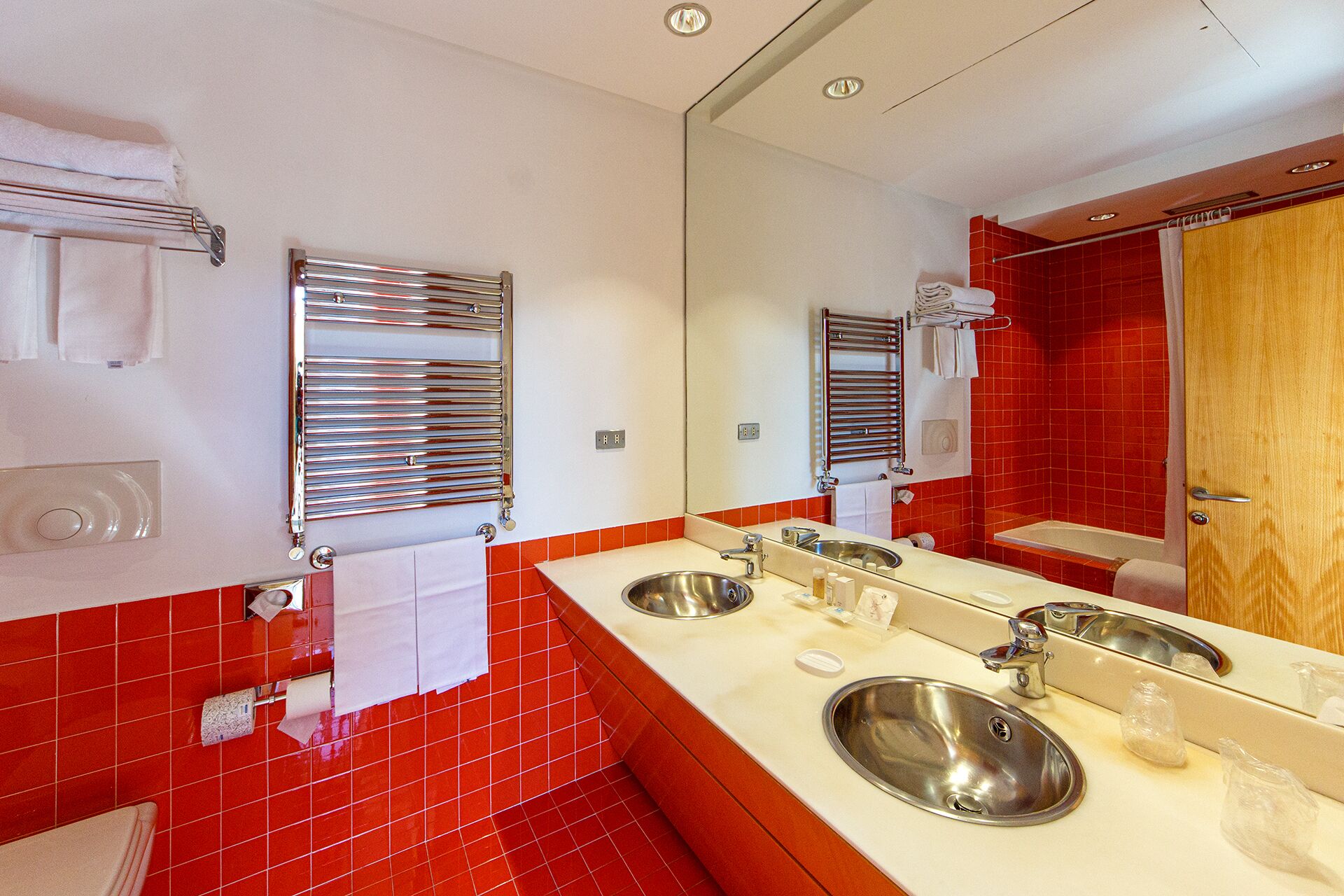 A modern bathroom with two sinks, a large mirror, and chrome towel racks.