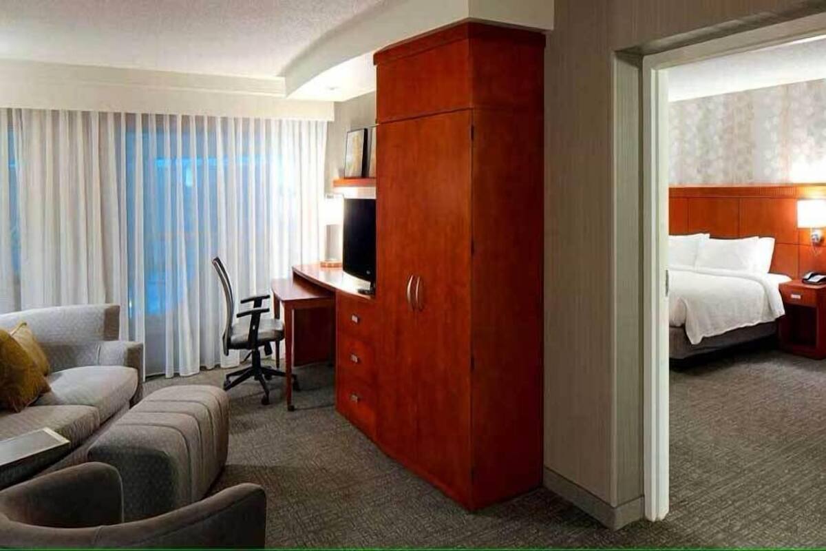 A hotel room with a desk, a wardrobe, a bed, and a television.