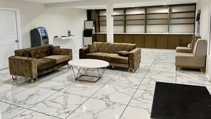 A spacious living area with a sofa set, a coffee table, and a built-in kitchen area with cabinets.