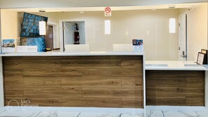 A reception desk with a wooden panel design, a 'No Smoking' sign, and a framed picture on the wall.