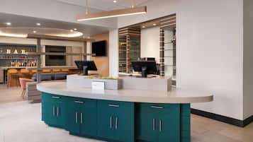 A modern bar area with a curved counter, teal cabinets, and a seating area with a sofa and chairs.