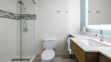 Un baño moderno con ducha envuelta en vidrio, inodoro blanco y tocador con espejo.