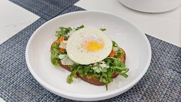 A white plate with a toasted bread topped with greens and a fried egg.