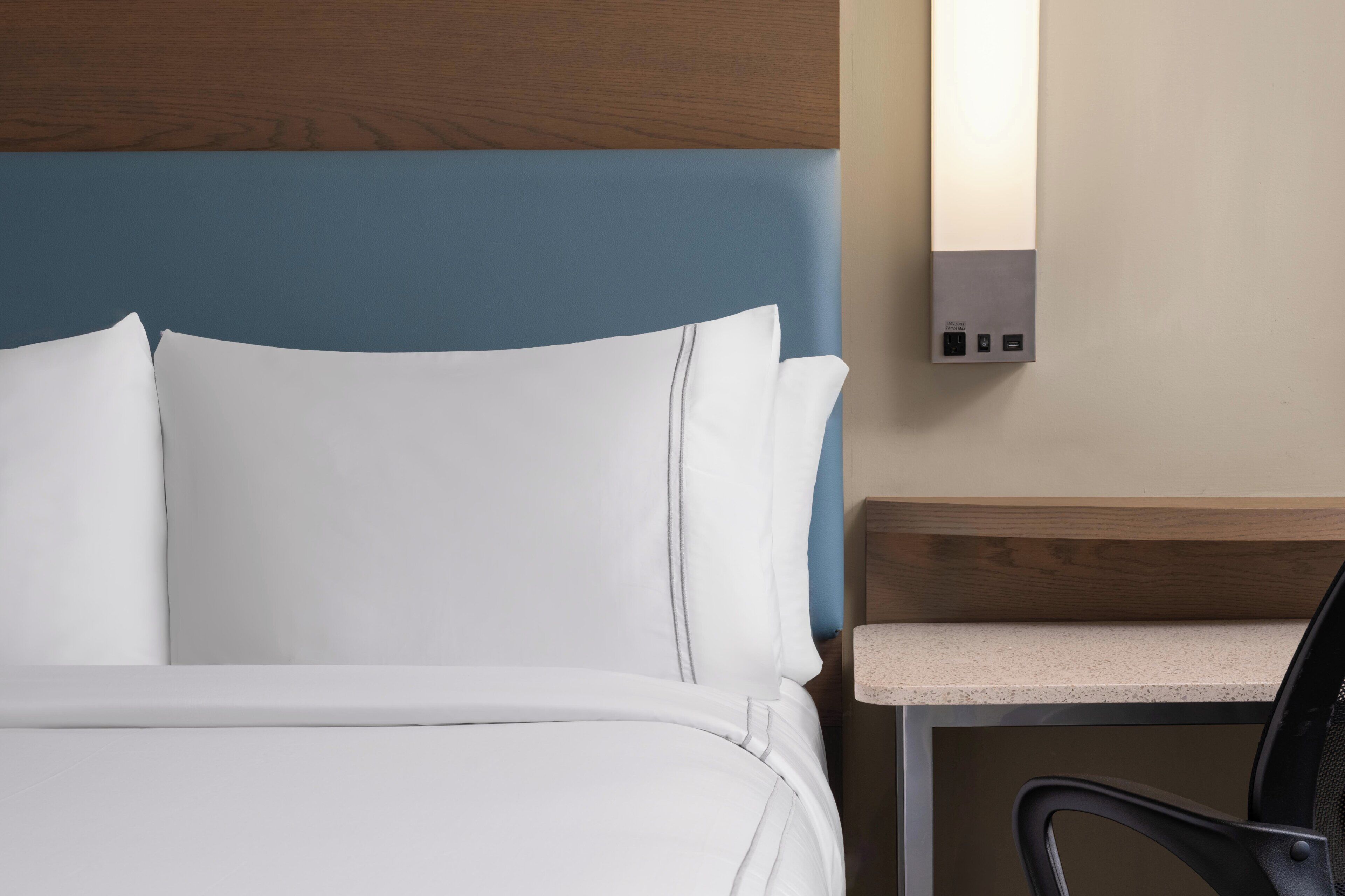 Habitación de hotel con una cama, una mesita de noche y un escritorio con una silla.
