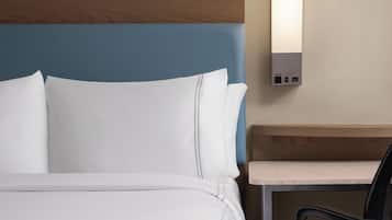 A hotel room with a bed, a nightstand, and a desk with a chair.
