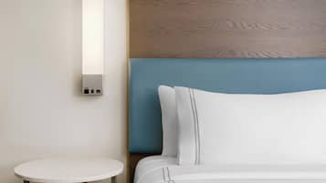 Una habitación de hotel con una cama, una mesa redonda y una lámpara fijada a la pared.
