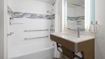 A modern bathroom with a bathtub, shower, vanity, and a large mirror.