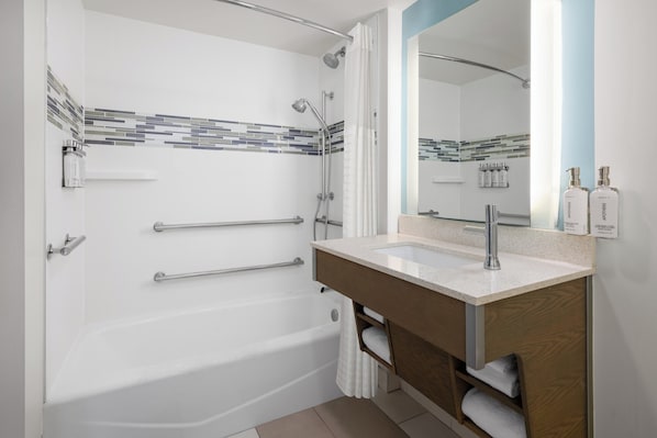 Un baño moderno con bañera, ducha, tocador y un espejo grande.