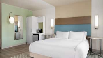 Een hotelkamer met een bed, een klein kitchenette, een spiegel en een ronde tafel.