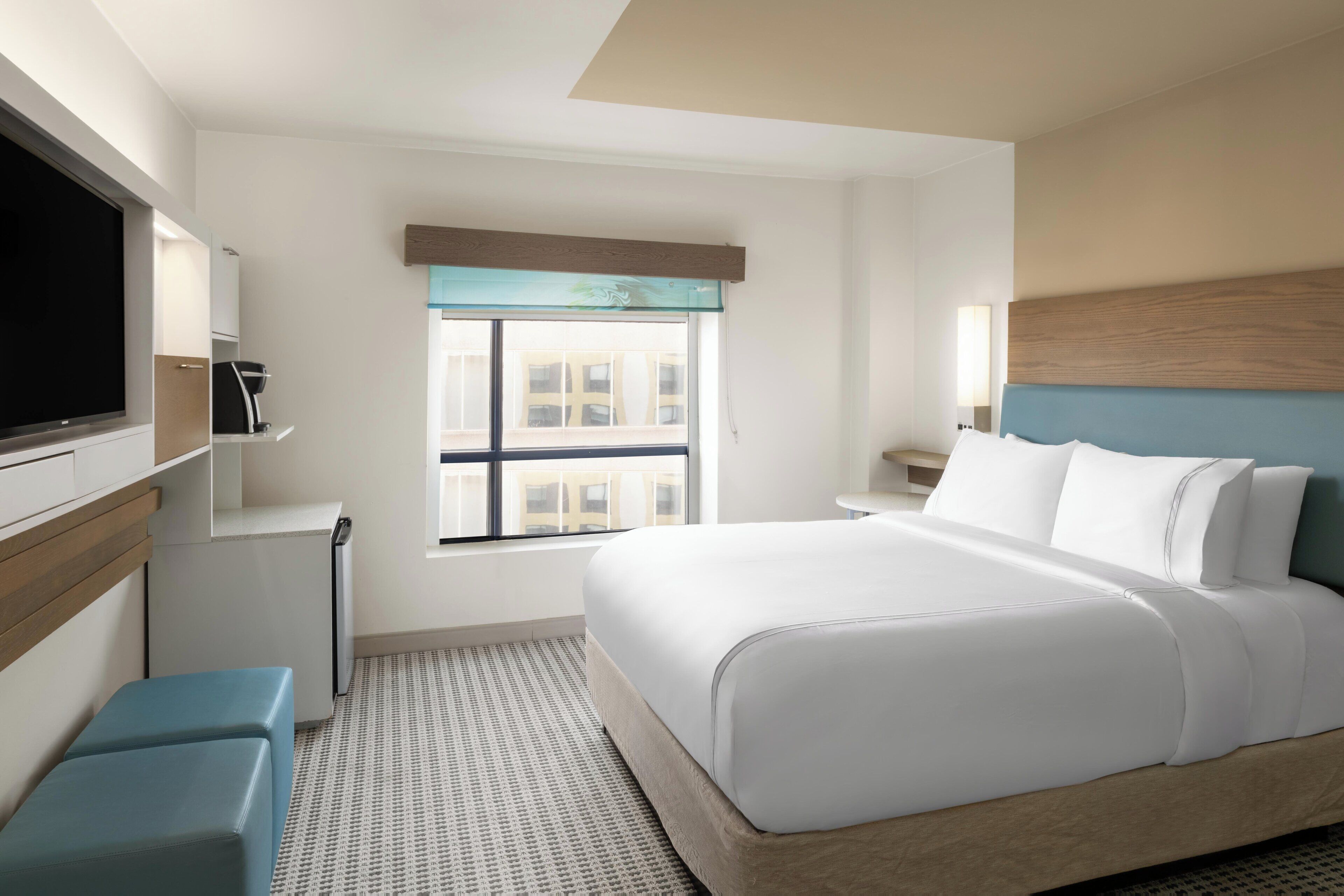 Une chambre d’hôtel avec un lit, une télévision, une fenêtre et un bureau.