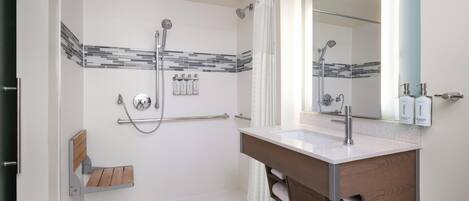 Un baño moderno con ducha, tocador con espejo y perchero.