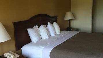 A hotel room with a bed, a nightstand with a telephone, and a lamp.