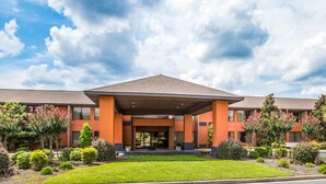 A modern hotel with a covered entrance, multiple floors, and a well-maintained garden.