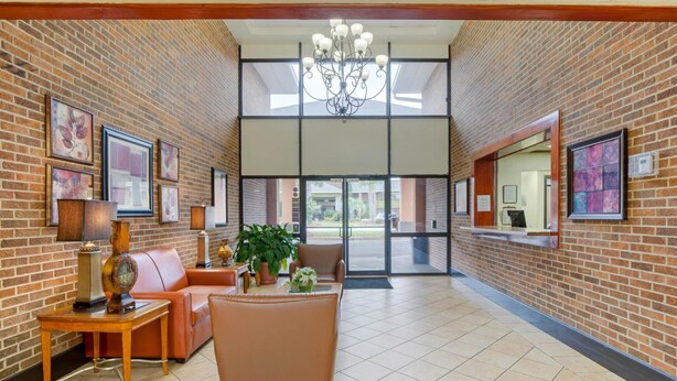 A lobby with brick walls, a chandelier, leather seating, and framed artwork.