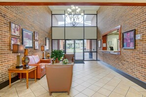 A lobby with brick walls, a chandelier, leather seating, and framed artwork.