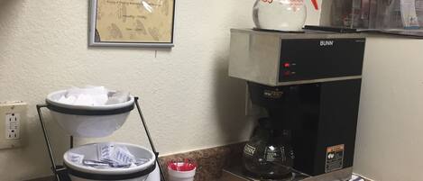 A kitchen with a coffee maker, a coffee dispenser, and a sign that says "Rise and Shine".