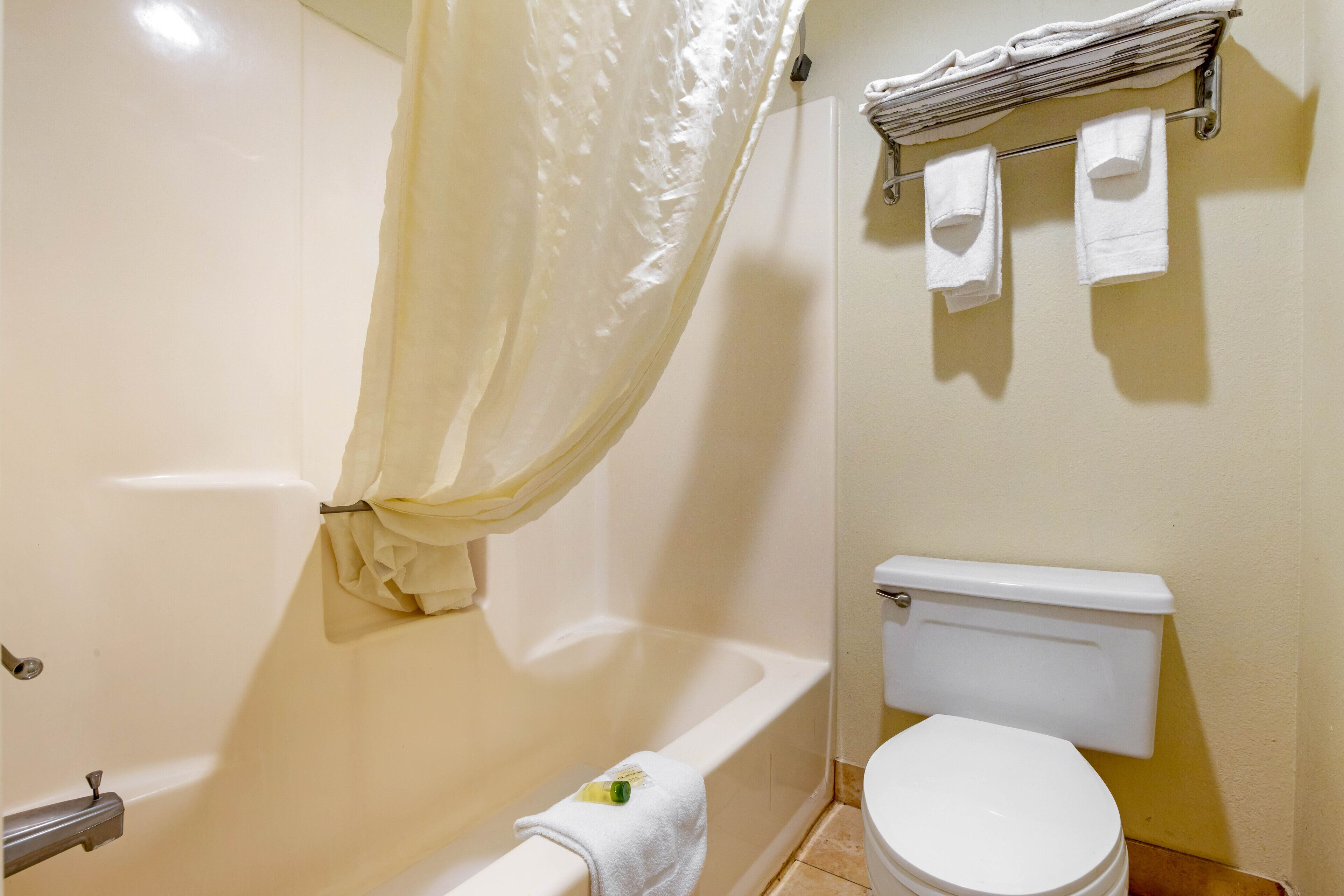 A bathroom with a bathtub, toilet, and a towel rack with towels.