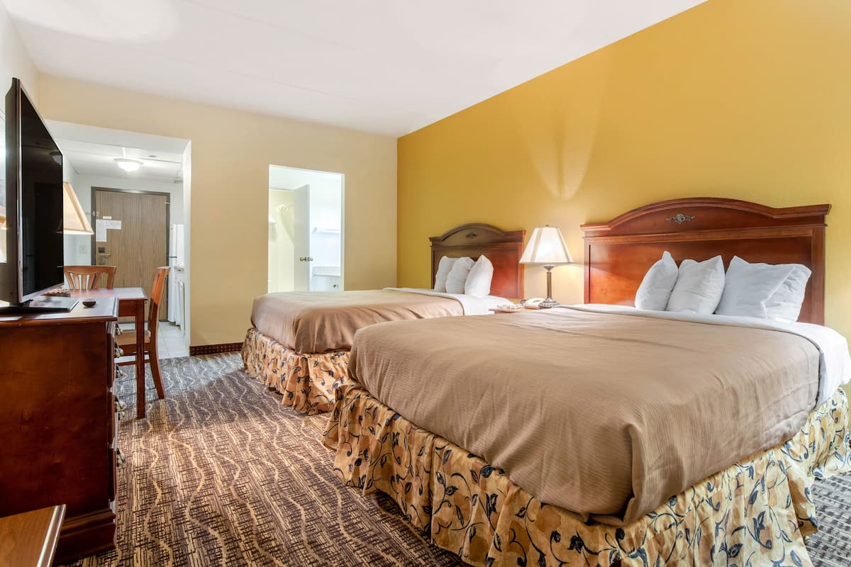 A hotel room with two beds, a desk, and a chair.