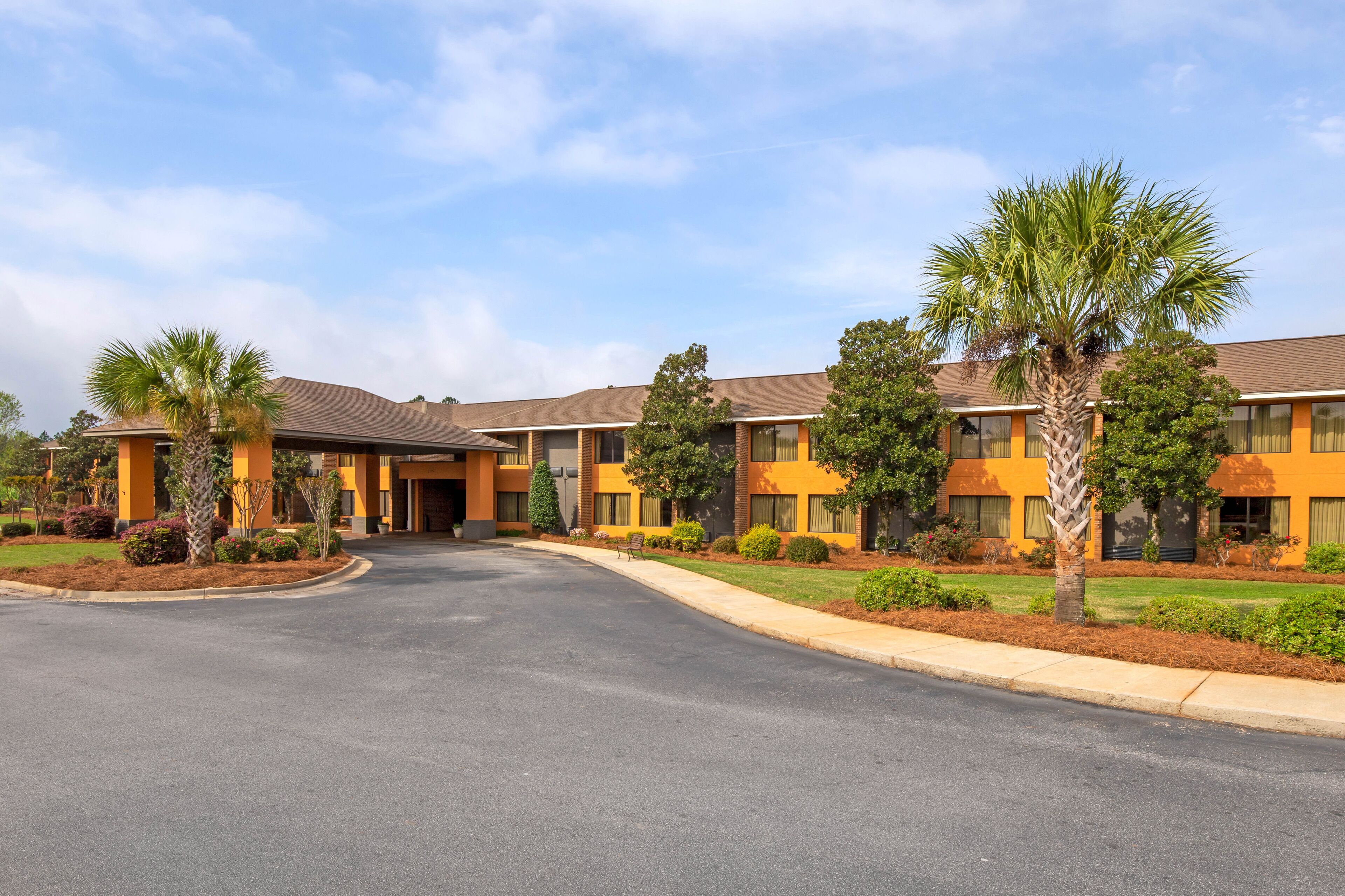 A hotel with a central courtyard, multiple-story buildings, and palm trees.