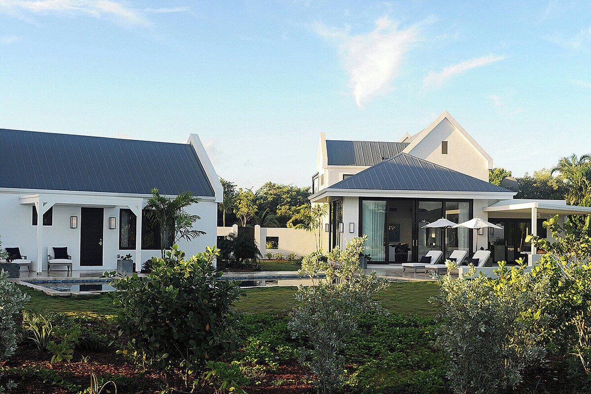 A modern two-story house with a large patio area, outdoor seating, and a well-maintained garden.