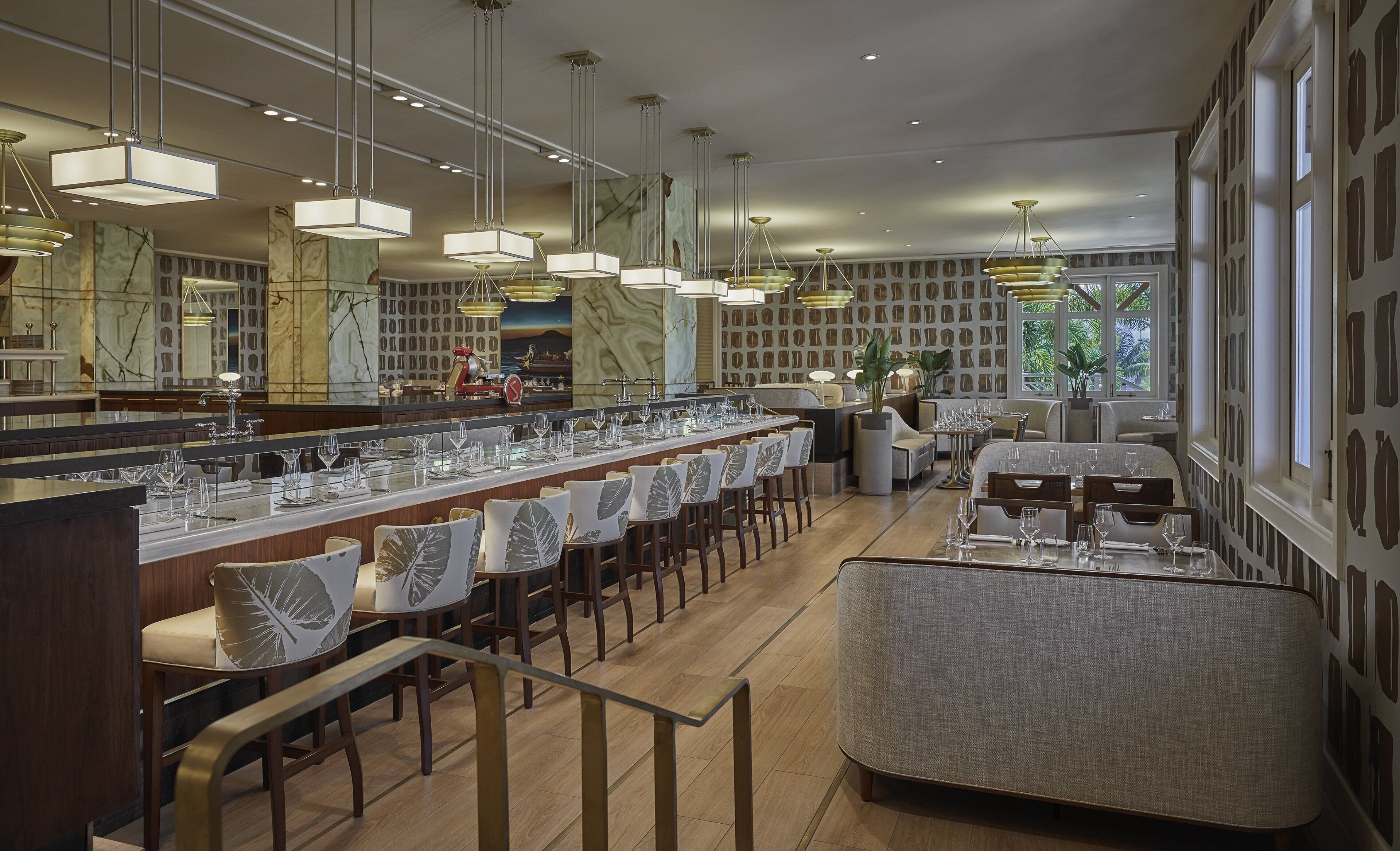 Interior moderno de restaurante con una barra alargada, varias zonas de estar e iluminación contemporánea.