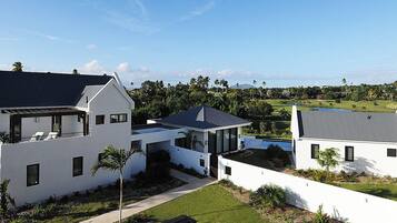 Un área residencial moderna con casas blancas, un cielo despejado y un campo de golf al fondo.
