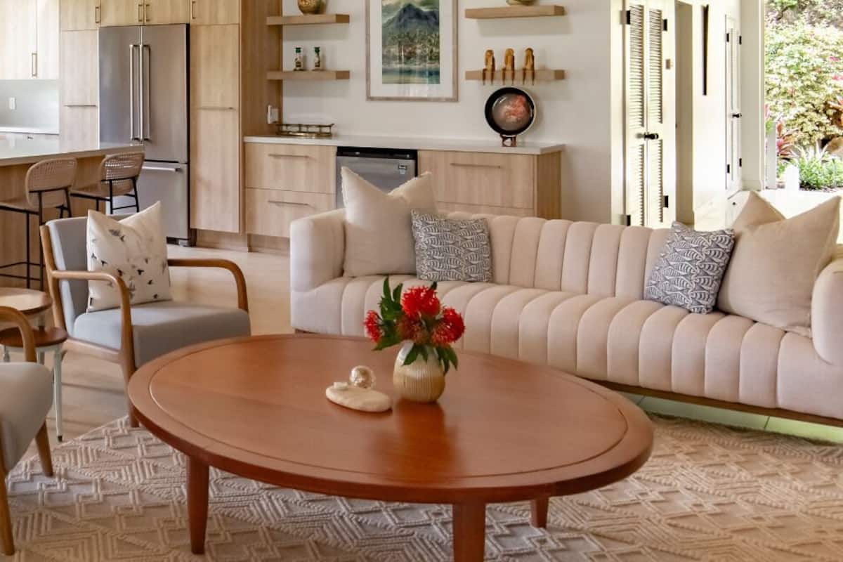 A modern living room with a sofa, chairs, a coffee table, and a kitchen area with a dining set.
