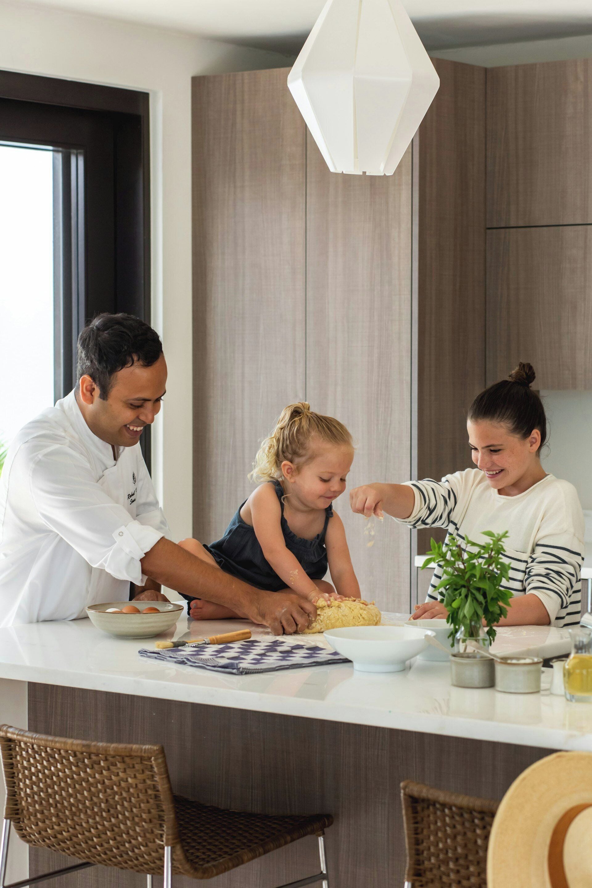 Una cocina moderna con una isla central, armarios de madera y una lámpara colgante.
