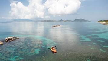 On aperçoit clairement une mer calme, avec un kayak au premier plan et un promontoire rocheux en arrière-plan.