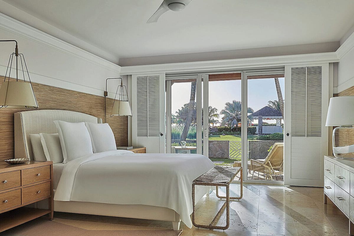 A bedroom with a bed, bedside tables, a lamp, and a view of the outdoors through a sliding glass door.