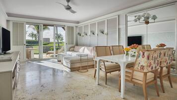 A spacious living area with a dining table, chairs, a sofa, and a television.